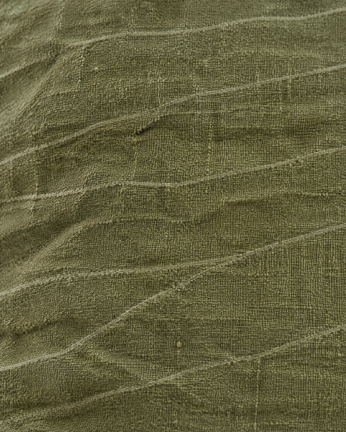 Macro close-up of the olive jacquard, fine sage lines wandering across crumpled matte olive linen cotton