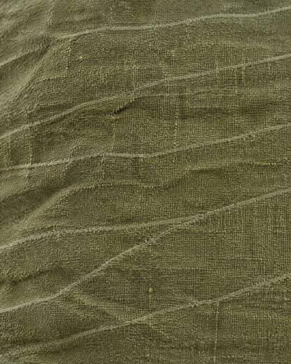 Macro close-up of the olive jacquard, fine sage lines wandering across crumpled matte olive linen cotton