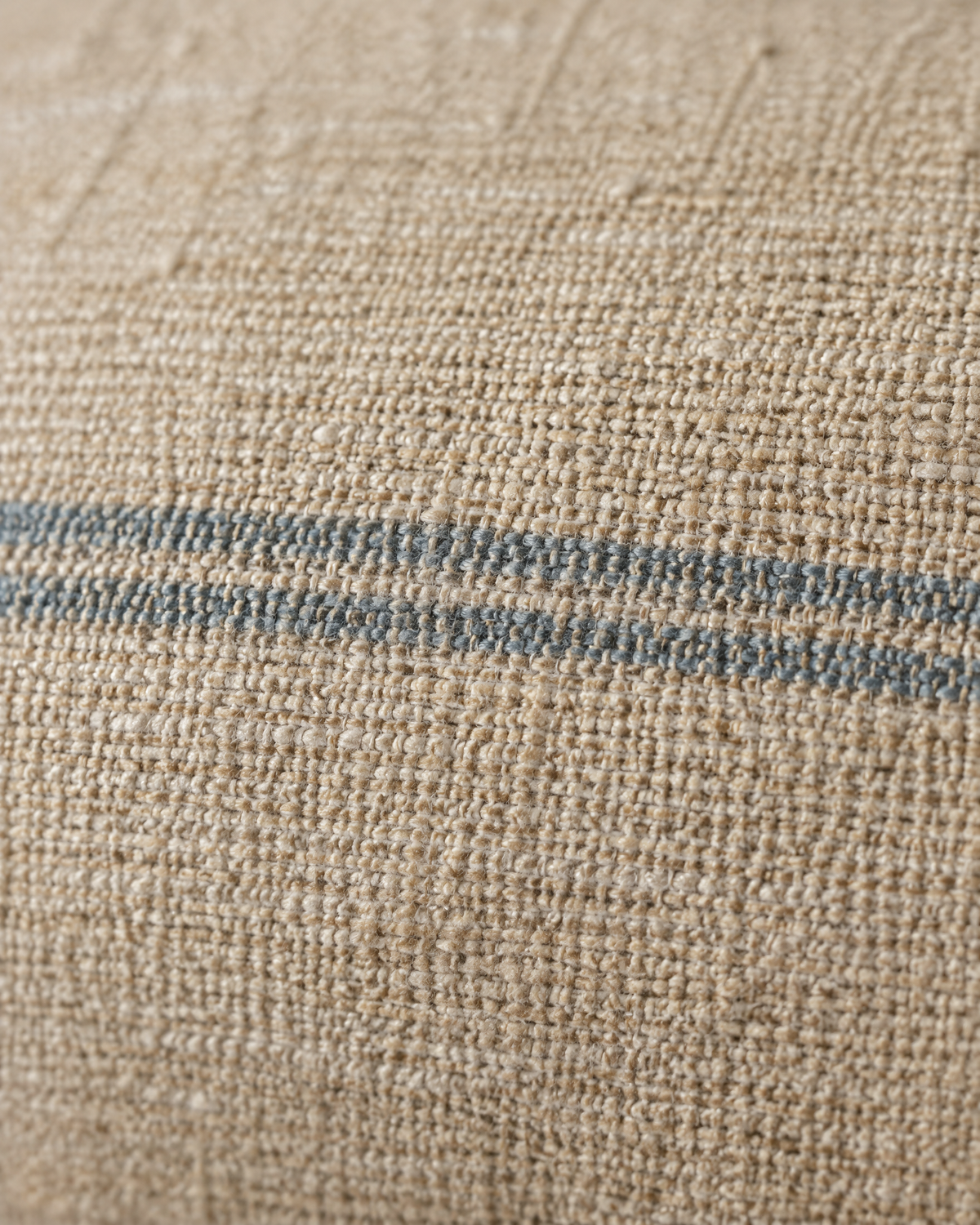Macro close-up of a thin sky-blue woven stripe on slubbed sand hemp-cotton