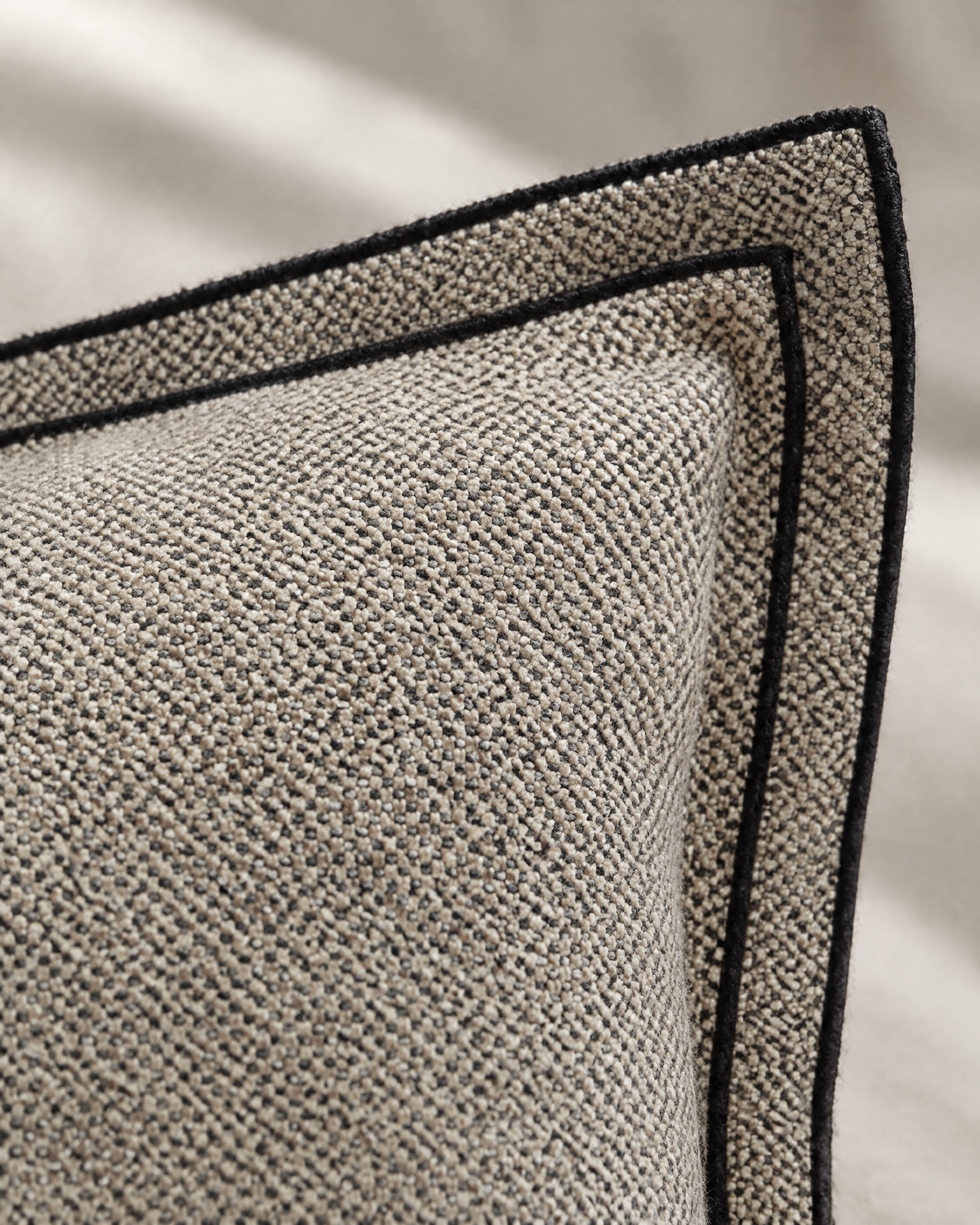 Macro close-up of the stone bird's-eye jacquard flange with its charcoal bound edge
