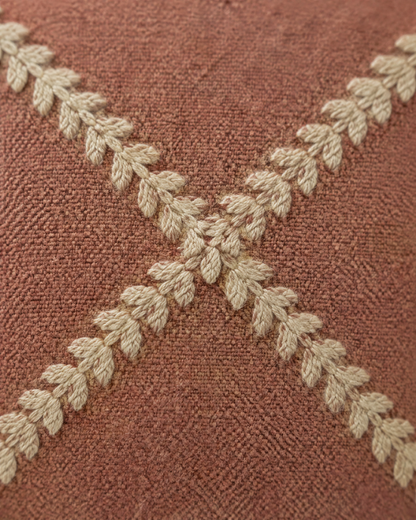 Macro close-up of the terracotta trellis lumbar, sand feather-stitch lines crossing on dusty terracotta cloth