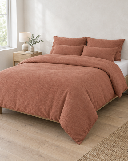 Terracotta cloud cotton duvet cover and pillowcases on an oak-framed bed in soft daylight