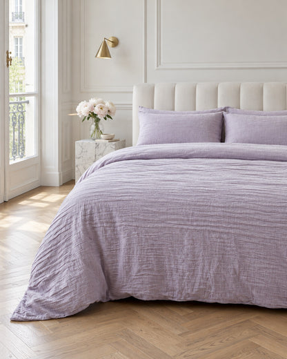 Lilac cloud cotton duvet cover in a Parisian bedroom with panelled walls and fresh peonies