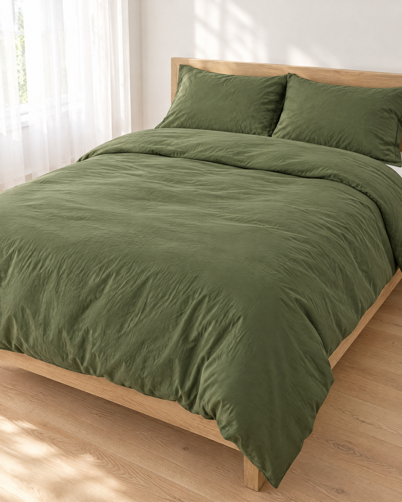 Olive plain cotton percale duvet cover on a made bed in a bright bedroom
