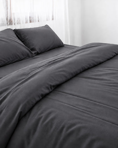 Charcoal Grey silky cotton duvet cover, grey 300 TC cotton sateen, turned back on a bed by a white sheer curtain