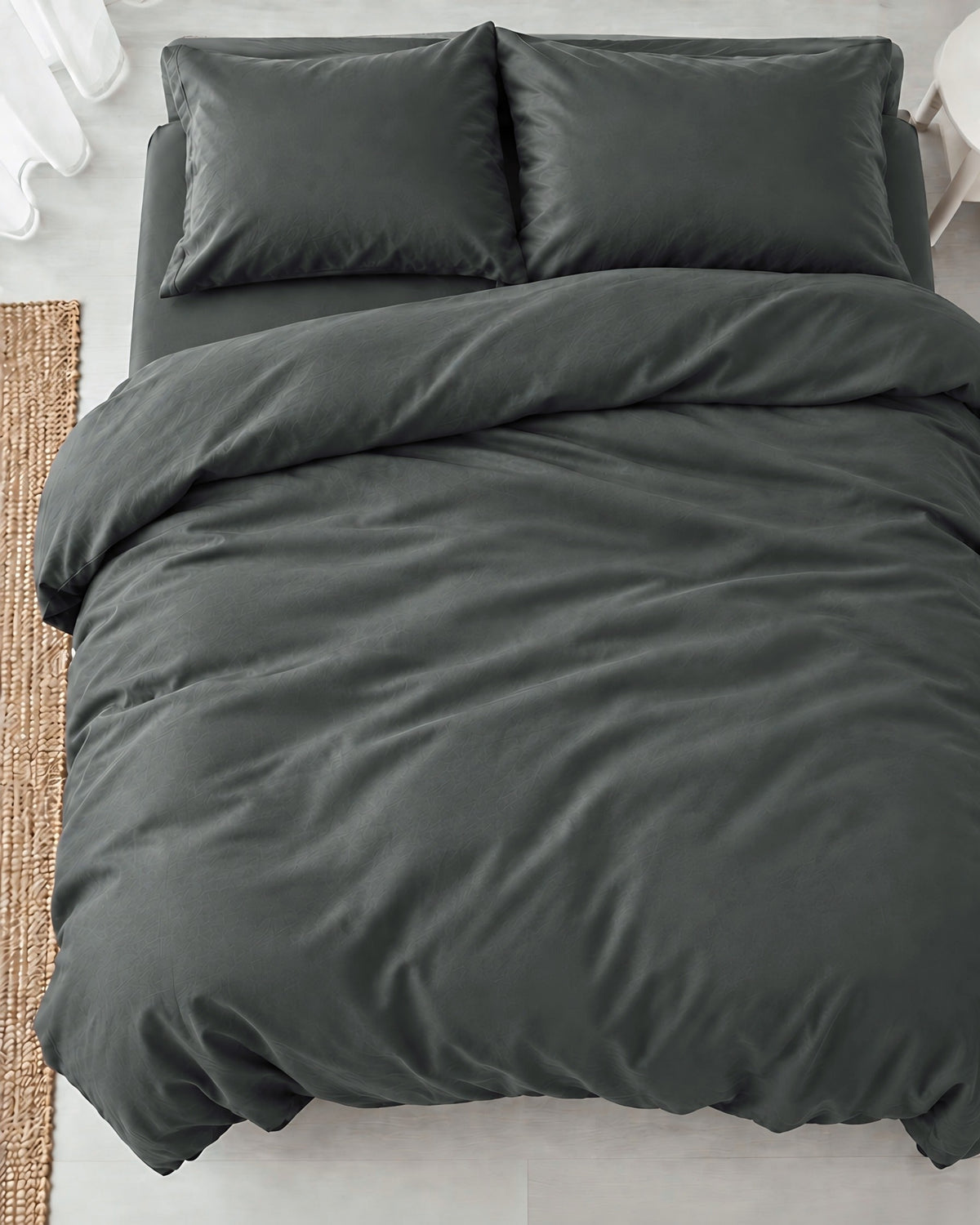 Overhead view of a Charcoal Grey silky cotton duvet cover, grey cotton sateen, with two matching pillows on a made bed