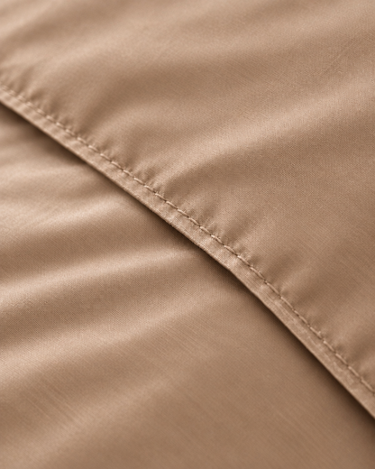 Macro of the stitched hem on a Light Beige silky cotton duvet cover, showing the beige sateen weave and sheen.