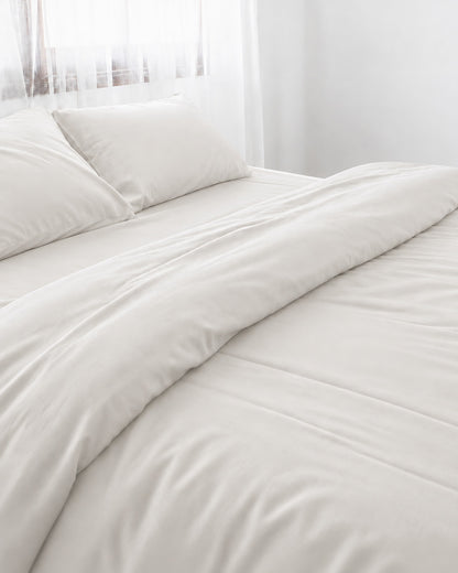 Milky White silky cotton duvet cover, white 300 TC cotton sateen, turned back on a bed by a white sheer curtain