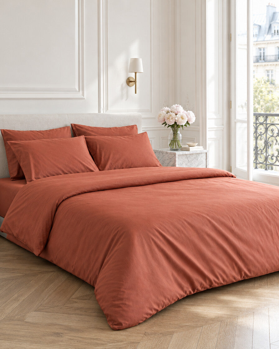 Terracotta silky cotton duvet cover in a Parisian bedroom with panelled walls and fresh peonies