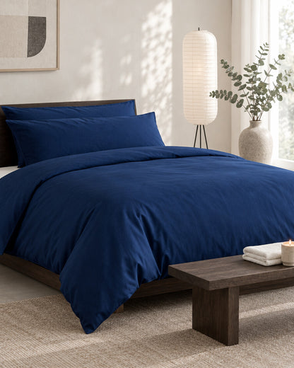 Navy silky cotton duvet cover in a calm Japandi bedroom on a low dark-oak bed