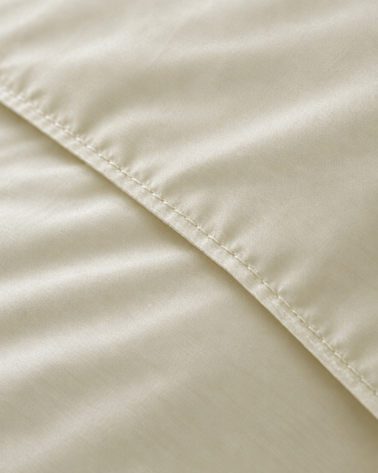 Macro of the stitched hem on a Vanilla silky cotton duvet cover, showing the cream sateen weave and sheen.