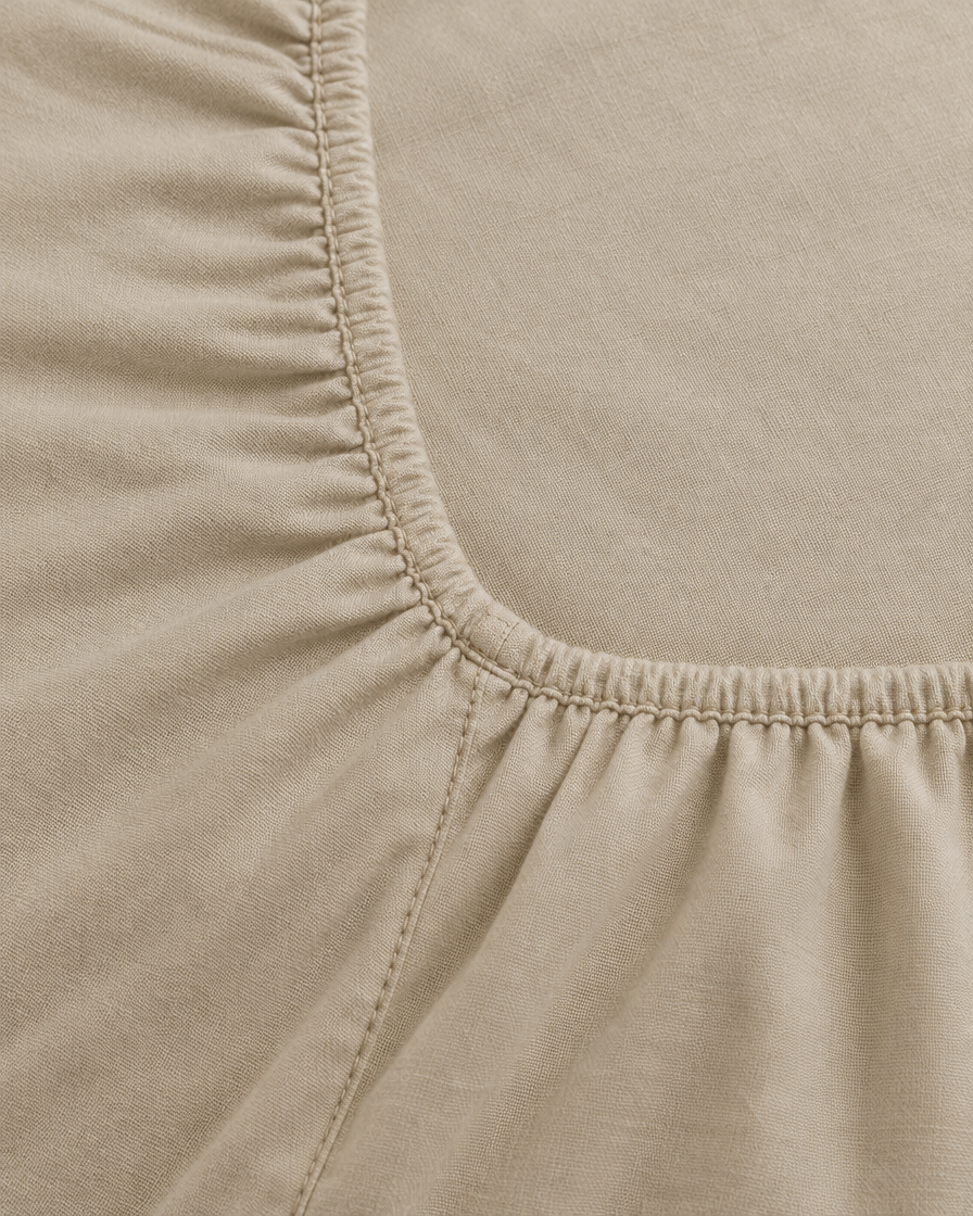 Close-up of elasticated corner and stitched edge of the fitted sheet in Beige Plain Cotton