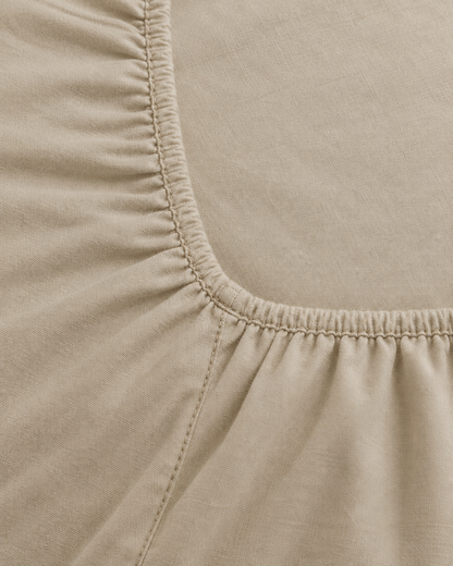 Close-up of elasticated corner and stitched edge of the fitted sheet in Beige Plain Cotton