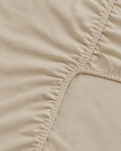Close-up of elasticated corner and stitched edge of the fitted sheet in Cream Plain Cotton