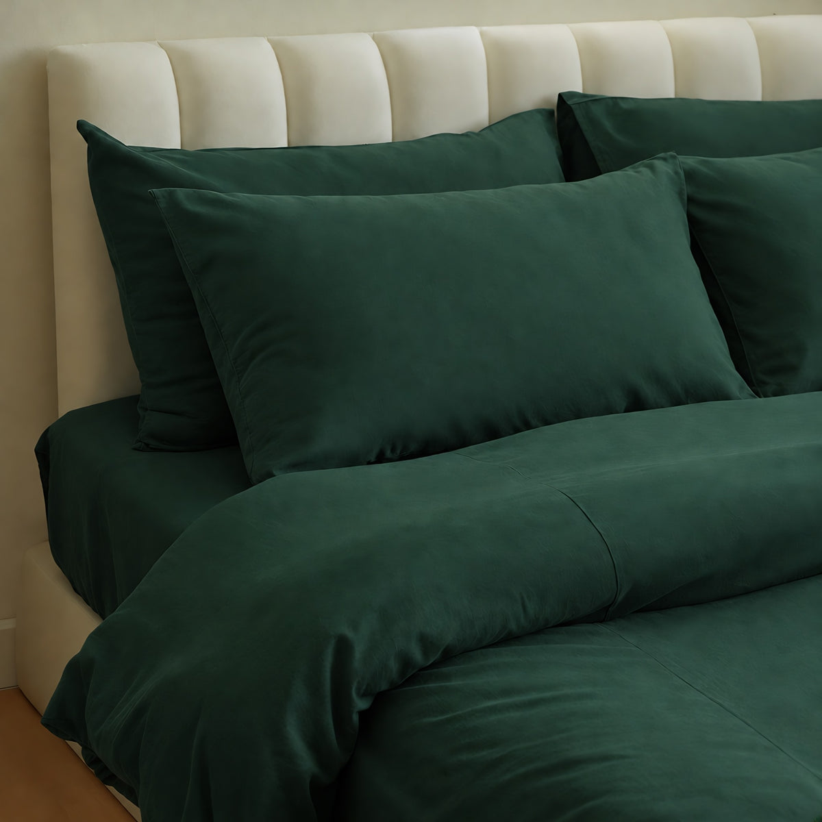 Forest Green plain cotton fitted sheet, pillowcases and duvet in deep bottle green on a cream bed