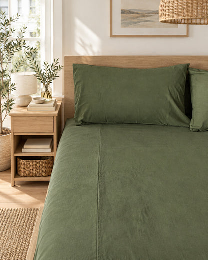 Olive green plain cotton fitted sheet and pillow, styled in a bright modern townhouse bedroom