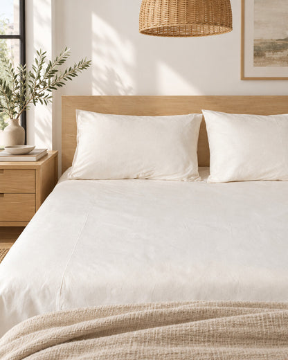 White plain cotton fitted sheet and pillows, styled in a bright modern townhouse bedroom