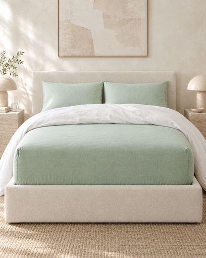 Mint Green Plain Cotton fitted sheet on a deep mattress under a folded-back white duvet, limewashed bedroom