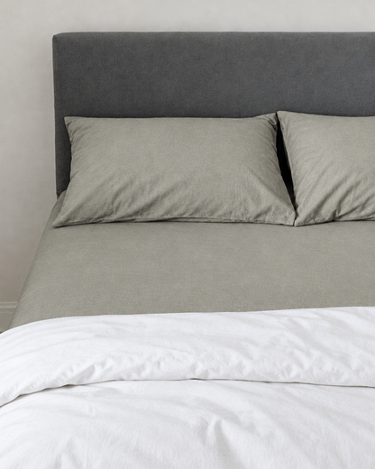 Mint Grey plain cotton fitted sheet and pillowcases under a white duvet, soft stone-sage tone