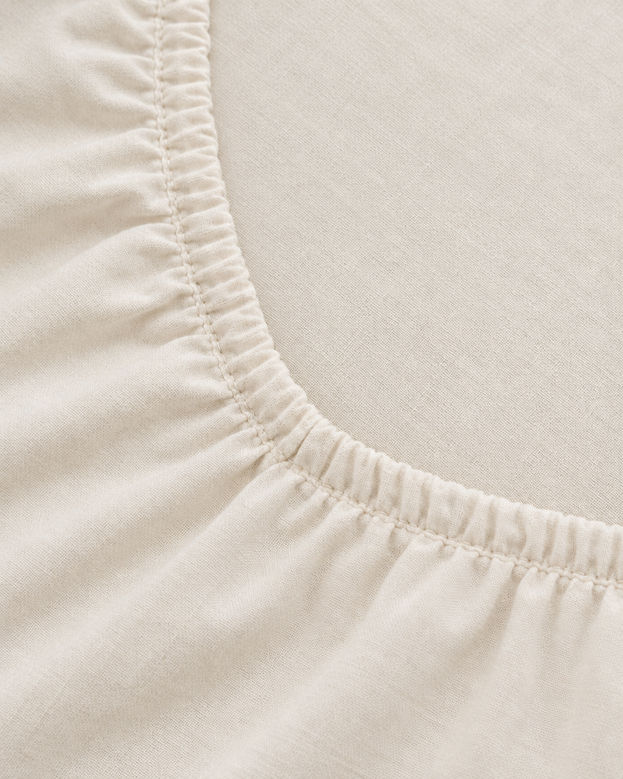 Close-up of elasticated corner and stitched edge of the fitted sheet in Off White Plain Cotton