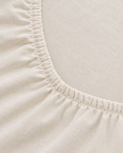 Close-up of elasticated corner and stitched edge of the fitted sheet in Off White Plain Cotton