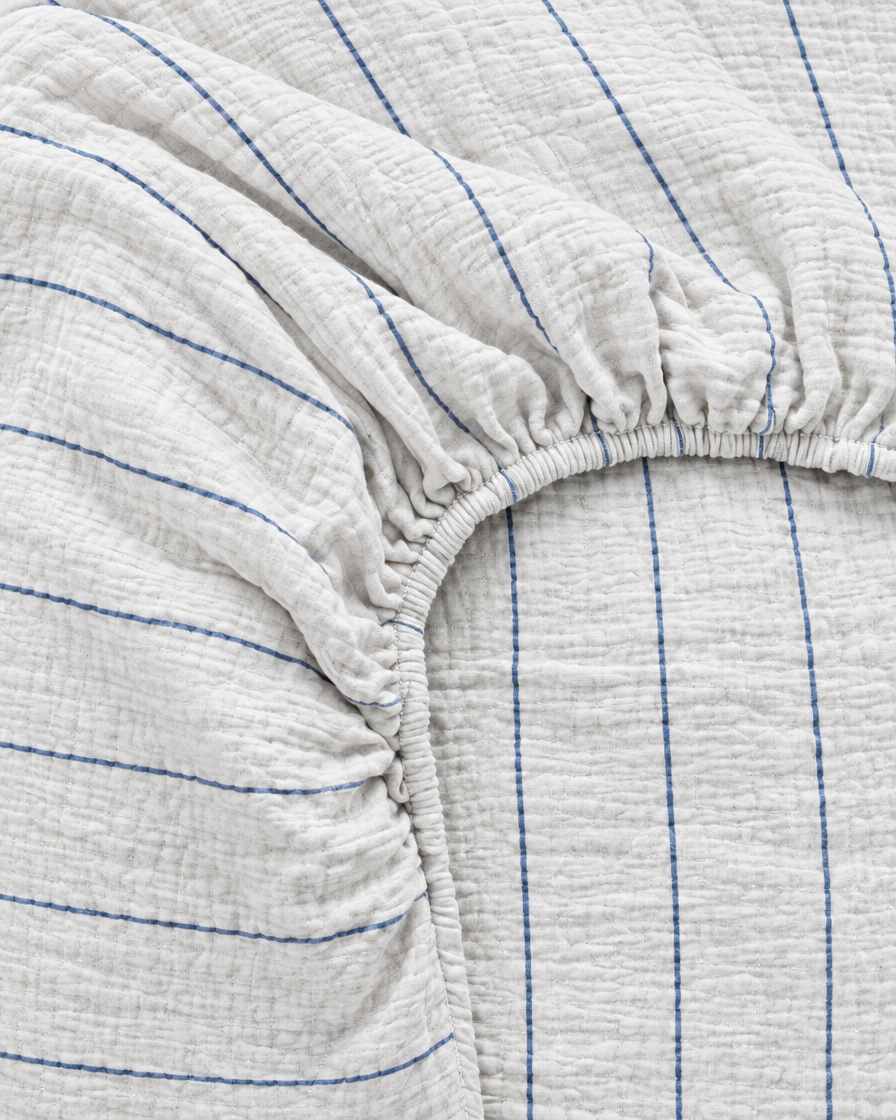 Close-up of elasticated corner and stitched edge of the fitted sheet in Blue Pinstripe Cloud Cotton