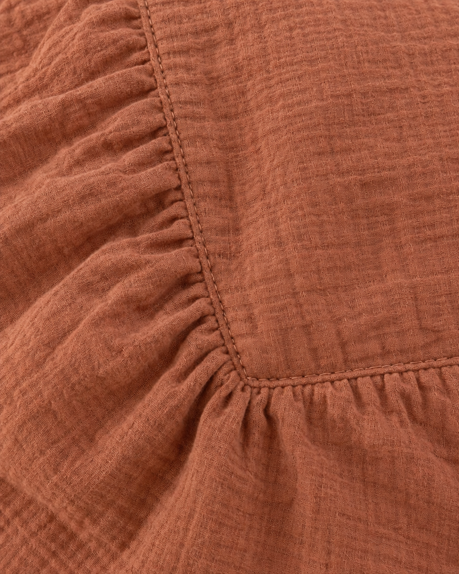 Close-up of elasticated corner and stitched edge of the fitted sheet in Copper Cloud Cotton