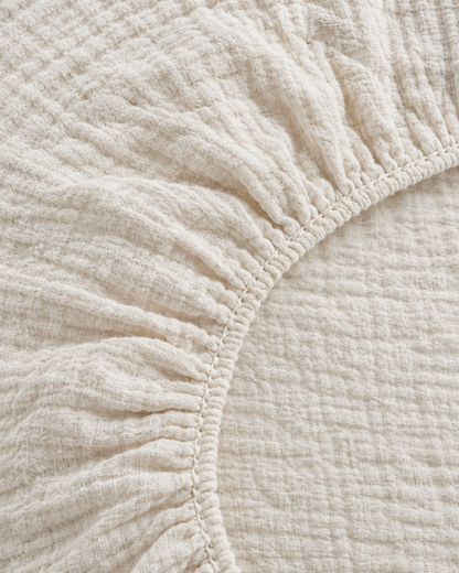 Close-up of elasticated corner and stitched edge of the fitted sheet in Cream Cloud Cotton