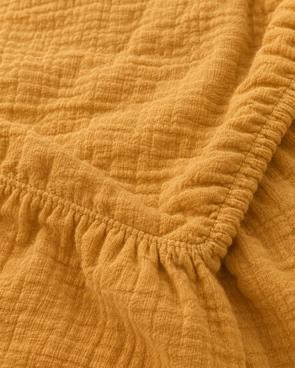 Close-up of elasticated corner and stitched edge of the fitted sheet in Mustard Cloud Cotton