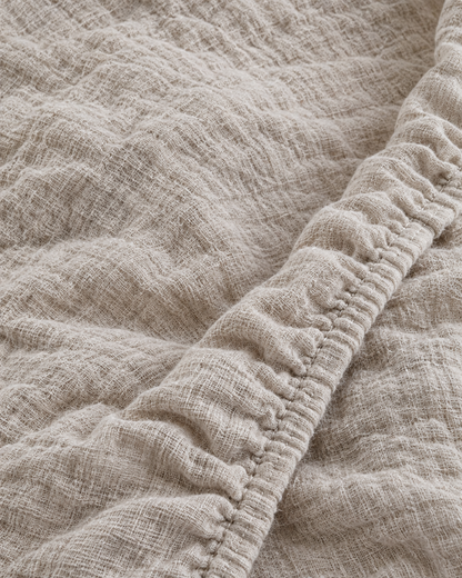 Close-up of elasticated corner and stitched edge of the fitted sheet in Oat Milk Cloud Cotton
