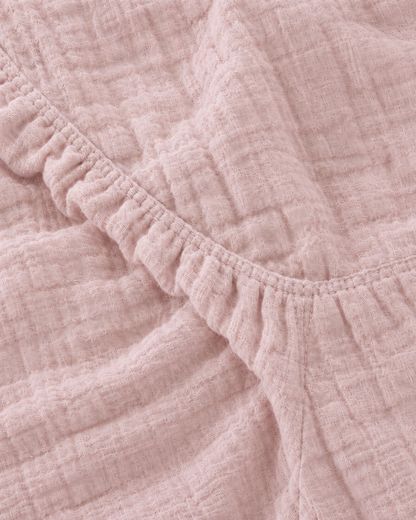 Close-up of the elasticated corner of the Pale Pink cloud cotton fitted sheet in soft dusty rose