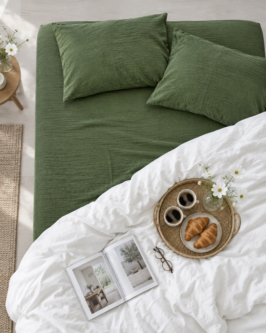 Olive green cloud cotton fitted sheet seen from above with a breakfast tray of coffee and croissants