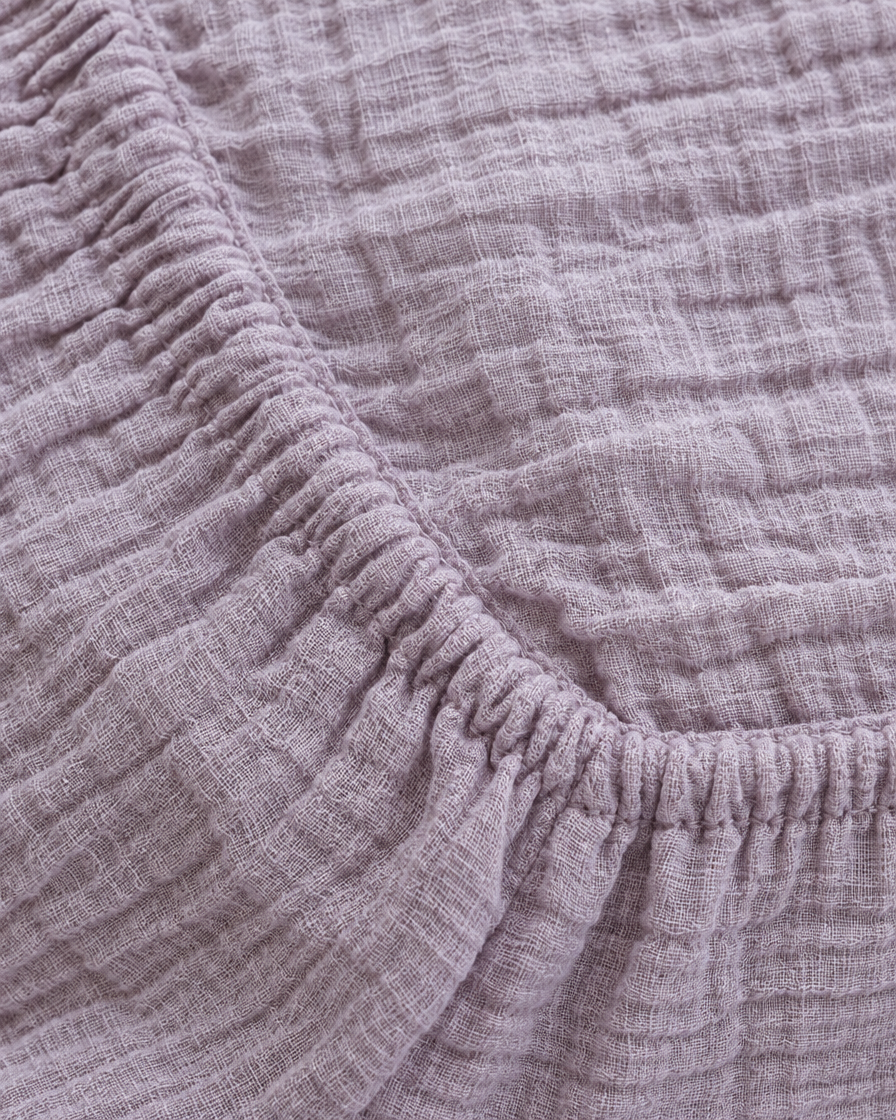 Close-up of elasticated corner and stitched edge of the fitted sheet in Taro Cloud Cotton