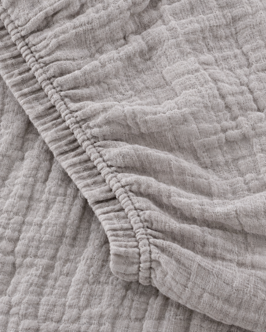Close-up of elasticated corner and stitched edge of the fitted sheet in Warm Grey Cloud Cotton