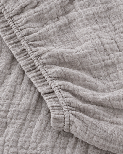 Close-up of elasticated corner and stitched edge of the fitted sheet in Warm Grey Cloud Cotton