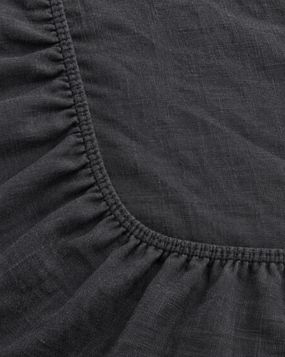 Close-up of elasticated corner and stitched edge of the fitted sheet in Charcoal Linen