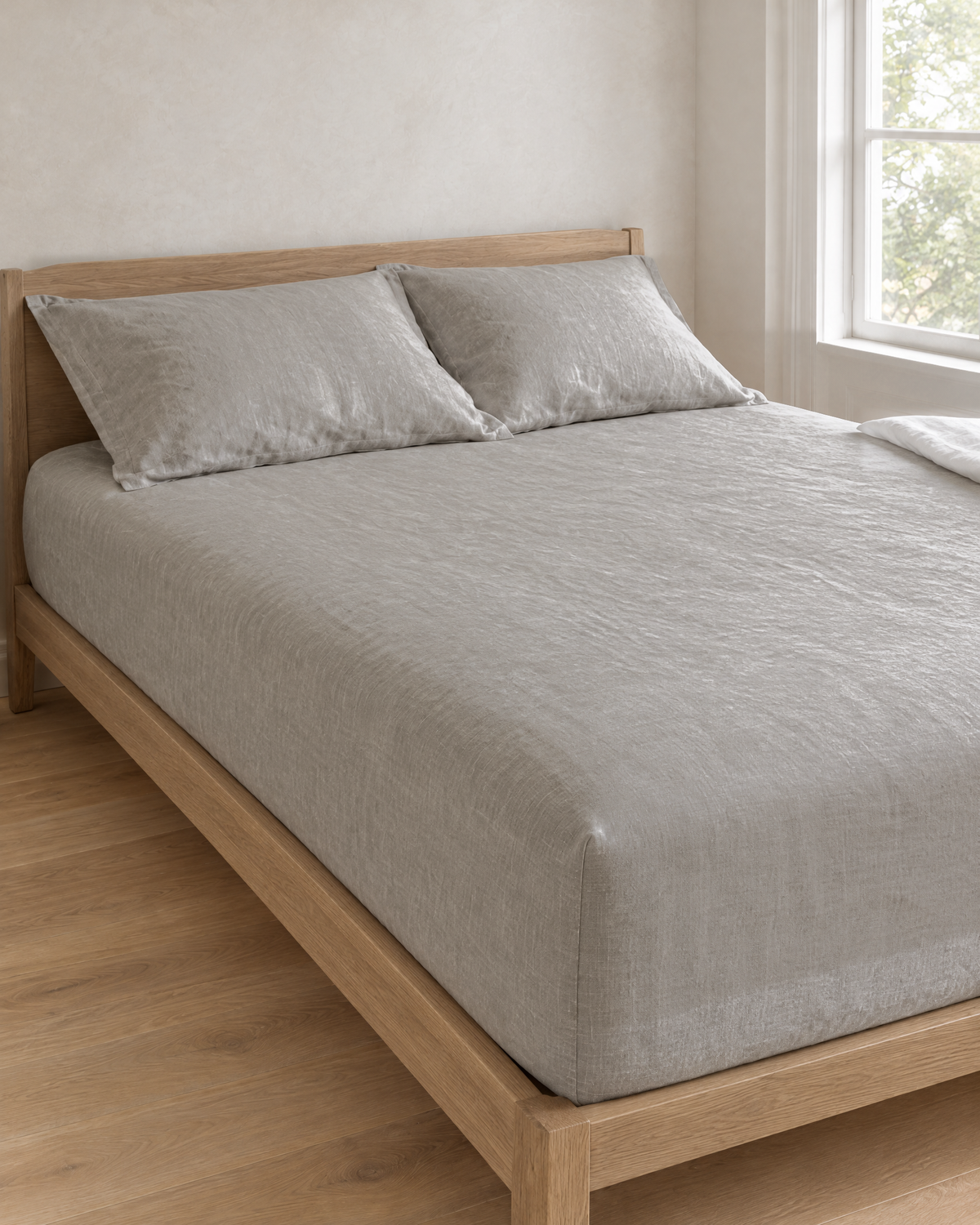 Mist linen fitted sheet on a made bed in a bright bedroom