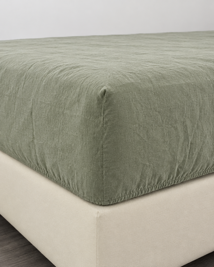 Sage green French linen fitted sheet on a mattress corner