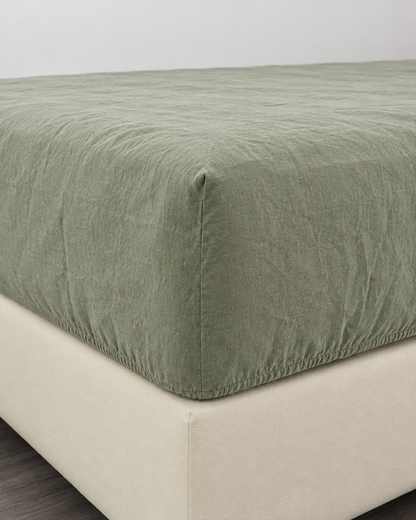 Sage green French linen fitted sheet on a mattress corner