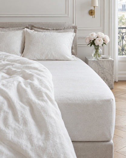 White French linen fitted sheet in a Parisian bedroom with panelled walls and fresh peonies