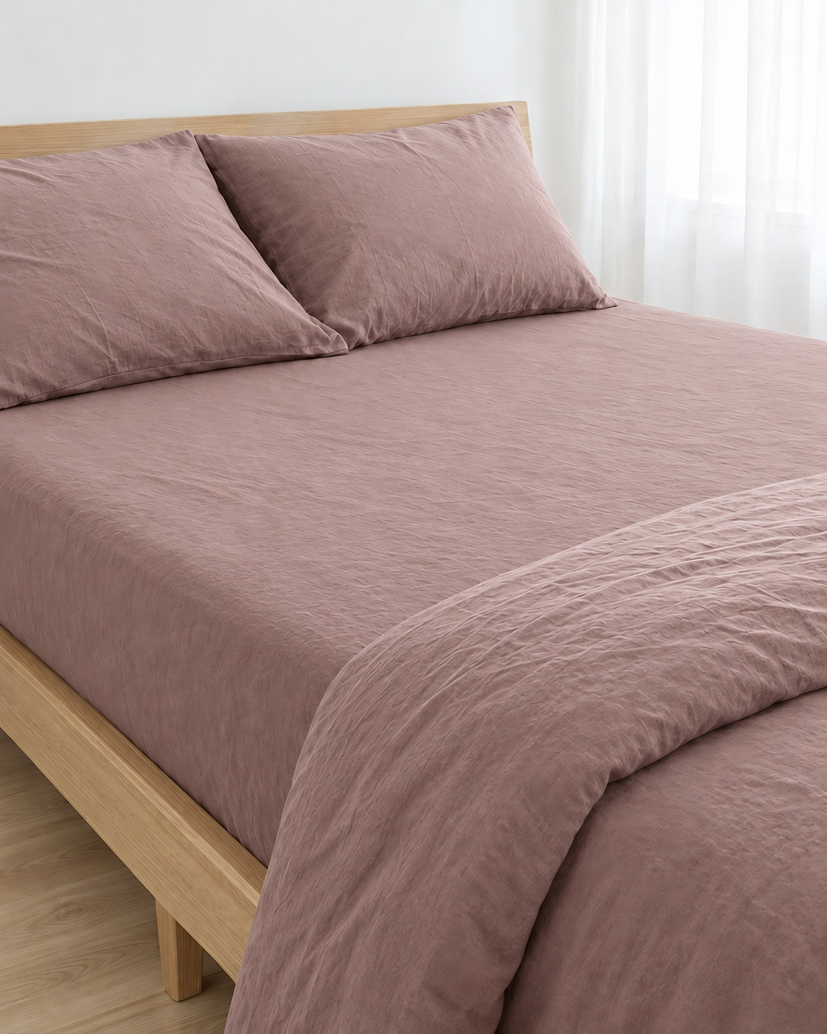 Dust Pink plain cotton fitted sheet pulled taut over a mattress on an oak bed with matching pillows