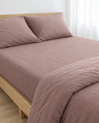 Dust Pink plain cotton fitted sheet pulled taut over a mattress on an oak bed with matching pillows