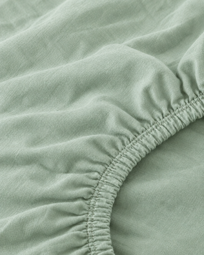 Macro of the gathered elastic corner of a Mint Green plain cotton fitted sheet.