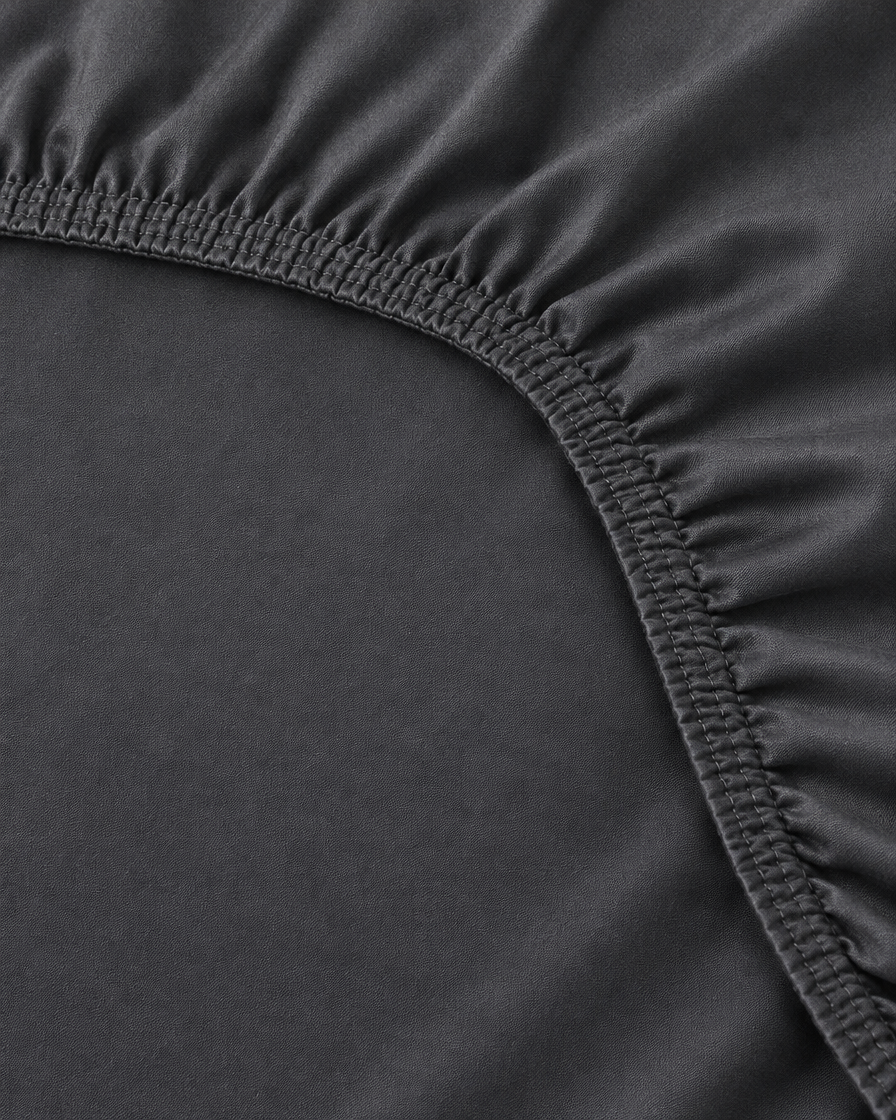 Close-up of elasticated corner and stitched edge of the fitted sheet in Charcoal Grey Silky Cotton