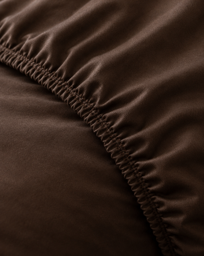 Macro of the gathered elastic corner of a Chocolate silky cotton fitted sheet.