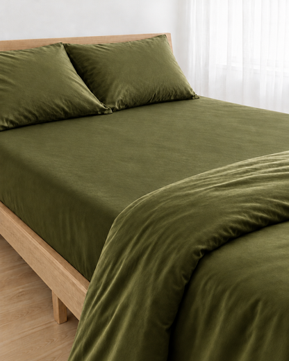 Juniper Green silky cotton fitted sheet pulled taut over a mattress on an oak bed with matching pillows.
