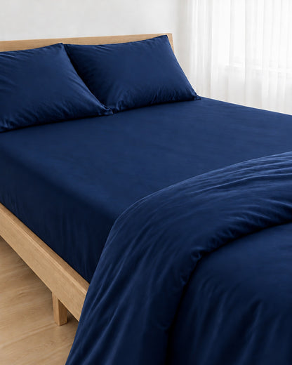 Marine Blue silky cotton fitted sheet, navy blue 300 TC sateen, pulled taut over a mattress on an oak bed
