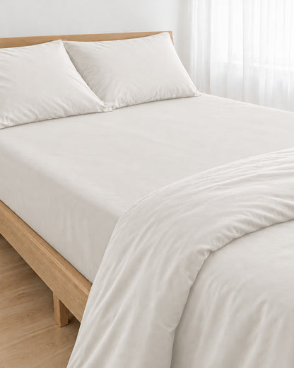 Milky White silky cotton fitted sheet, white 300 TC sateen, pulled taut over a mattress on an oak bed