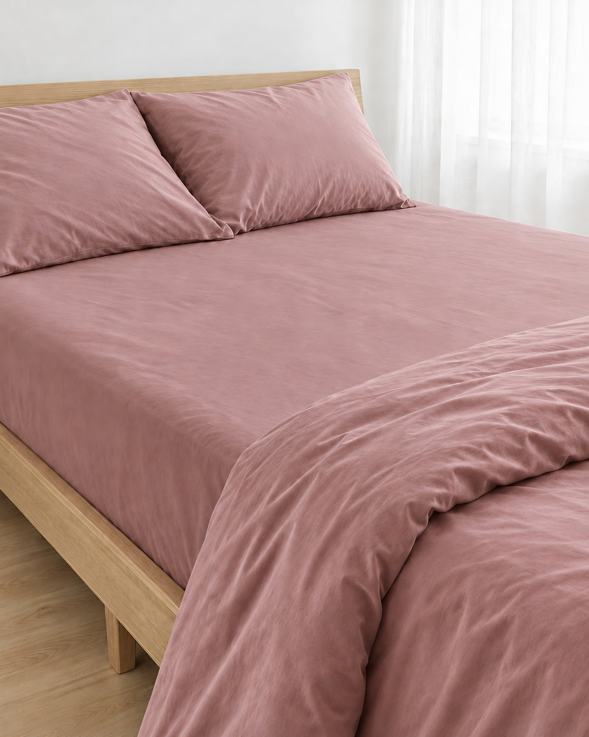 Rose Pink silky cotton fitted sheet pulled taut over a mattress on an oak bed with matching pillows