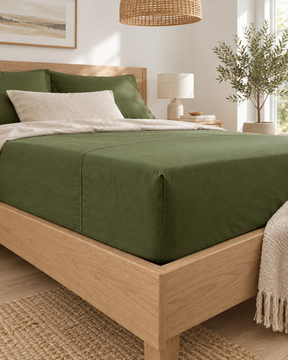 Olive green plain cotton sheet, styled in a bright modern townhouse bedroom